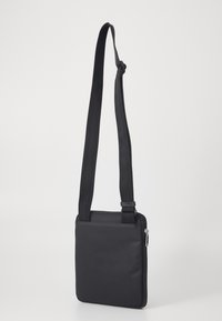 Black messenger bag made of durable fabric. Features an adjustable strap, smooth zipper, and sleek rectangular shape with a textured surface.