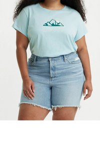 Světle modré tričko s grafikou hory a textem "Levi's"; spárováno se světle modrými džínovými šortkami s roztrhaným lemem a vysokým pasem.