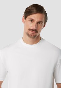 Witte t-shirt met korte mouwen en een ronde hals, gemaakt van gladde katoenstof. Eenvoudig ontwerp, zonder patronen of hardware.