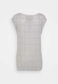 Blouse à manches courtes en tissu léger, présentant un motif à pois noir et blanc, un col rond et un bas froncé au niveau de la taille.