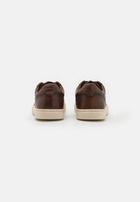 Brązowe skórzane sneakersy o gładkim wykończeniu, z kremowymi gumowymi podeszwami i zaokrąglonym designem. Posiadają przeszywane akcenty i wyściełany obszar pięty.