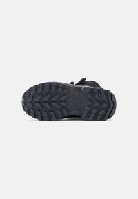 Μαύρη αθλητική σόλα παπουτσιού με ανθεκτικό σχέδιο πέλματος, σχεδιασμένη για πρόσφυση με βαθιές αυλακώσεις και ανθεκτικό καουτσούκ.