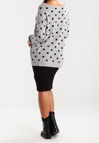 Grå tröja med svarta prickar, oversize passform, ribbad fåll. Kombinerad med en svart ribbad kjol och svarta ankelboots.