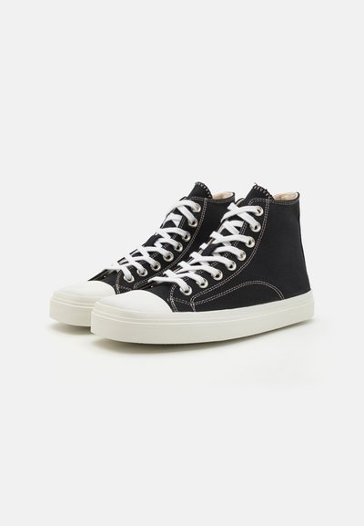 Black canvas high-top sneakers with white rubber soles, contrasting stitching, and white laces. Rounded toe with a smooth texture.