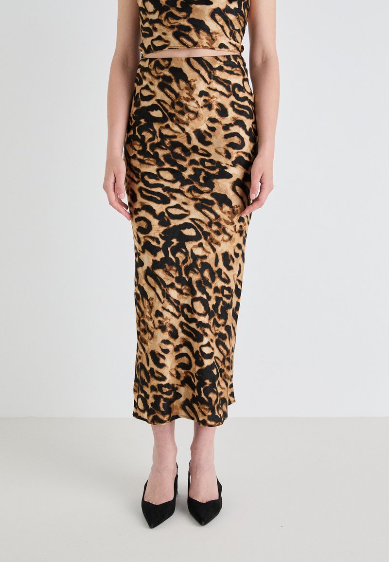 Krilo midi z leopardskim vzorcem, izdelano iz gladkega materiala, z oprijetim krojem in stranskim razporkom. Manekenka nosi črne elegante čevlje s koničastim nosom.