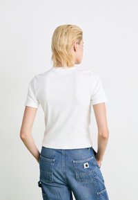 Hvid tætsiddende kortærmet t-shirt med ribbet tekstur og rund halsudskæring, parret med blå cargo-bukser med lappe-lommer.