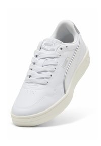 Valged nahast tõuksisneakerid siledast tekstuurist, paelteltud disain ja kerge kummitald. Omab väikest logo keelel ja küljel.