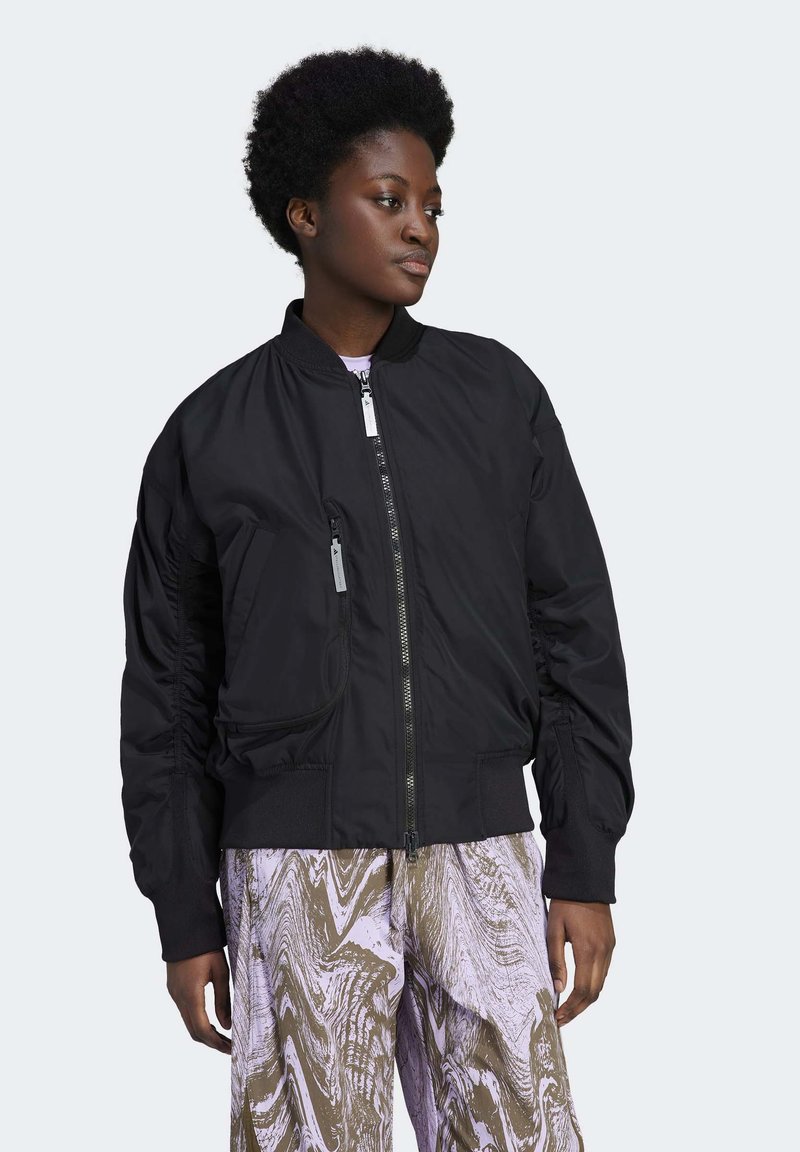 Fekete bomber dzseki cipzárral elöl, rugalmas mandzsettákkal és oldal zsebekkel, sima textúrával és enyhén ráncolt ujjal.