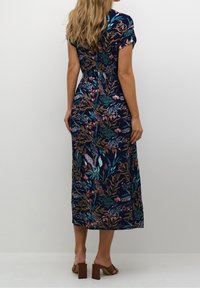 Robe maxi bleu marine à fleurs avec manches courtes, présentant une taille cintrée et une jupe fluide, soulignée par des motifs colorés de feuilles et de fleurs.