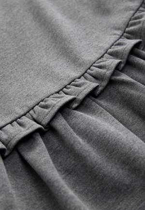 Grijze stof met een zachte textuur. Heeft geplooide ruches langs de rand, wat zorgt voor een gelaagde uitstraling. Eenvoudig en licht ontwerp.