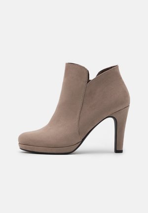 Beige ruskindsankelstøvle med en rundet tå, lav frontskæring og en 10 cm stiletthæl. Har et sømløst design uden synlige metaldele.