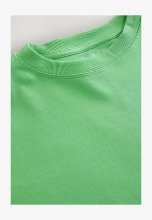 T-shirt en coton vert avec col rond côtelé, texture lisse et tissu léger. Aucune motif ni accent visible.