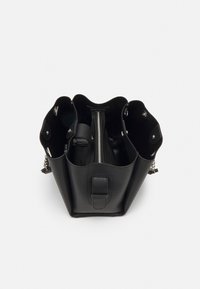 Černá kožená kabelka typu tote s otevřeným vrchem, obsahující dvě boční kapsy, centrální přihrádku na zip a kovové doplňky.