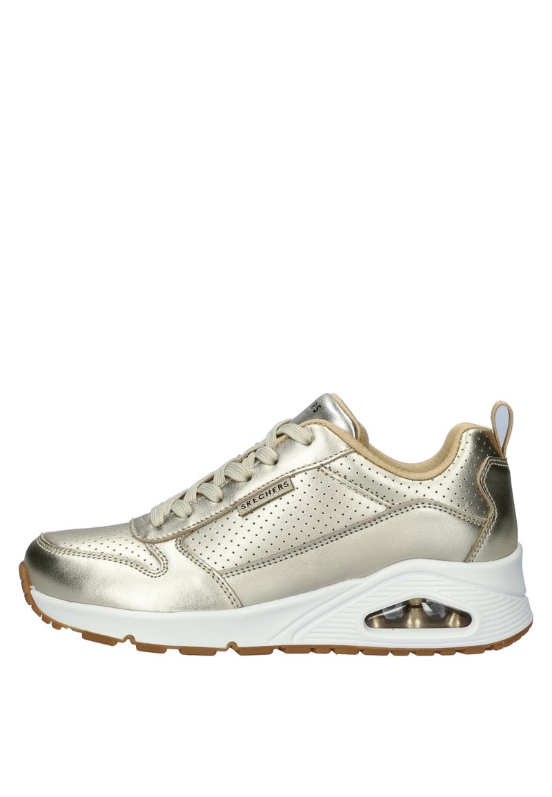 Baskets métalliques dorées avec des détails perforés, accents crème, semelle blanche et amorti visible dans le talon. Design classique à lacets.