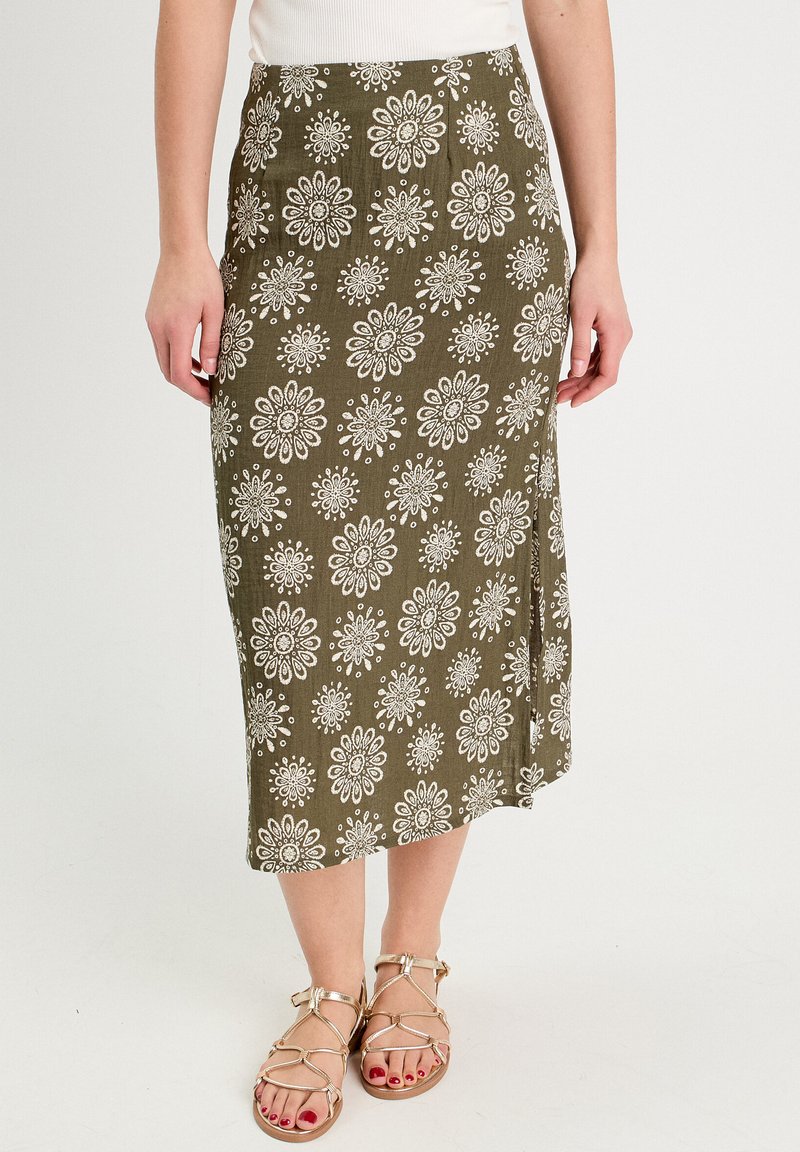 Jupe midi vert olive avec motif floral blanc, fabriquée en tissu léger. Elle présente une coupe droite et une fente sur le côté pour plus de liberté de mouvement.
