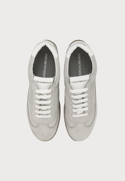 Paire de baskets Emporio Armani gris clair avec des lacets blancs et une languette blanche marquée, vues de dessus sur fond blanc.