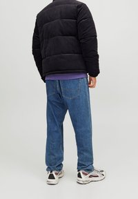 Czarna kurtka pikowana z sztruksu, niebieskie dżinsy i białe trampki z czarnymi i czerwonymi akcentami. Charakteryzuje się luźnym krojem i widocznymi detalami szwów.