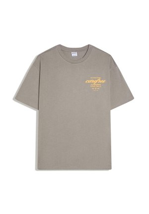 Taupe Kurzarm-T-Shirt mit rundem Ausschnitt und gelbem Text auf der Brust mit der Aufschrift „Zu beschäftigt damit, sorglos zu sein, um deine Anrufe zu beantworten."