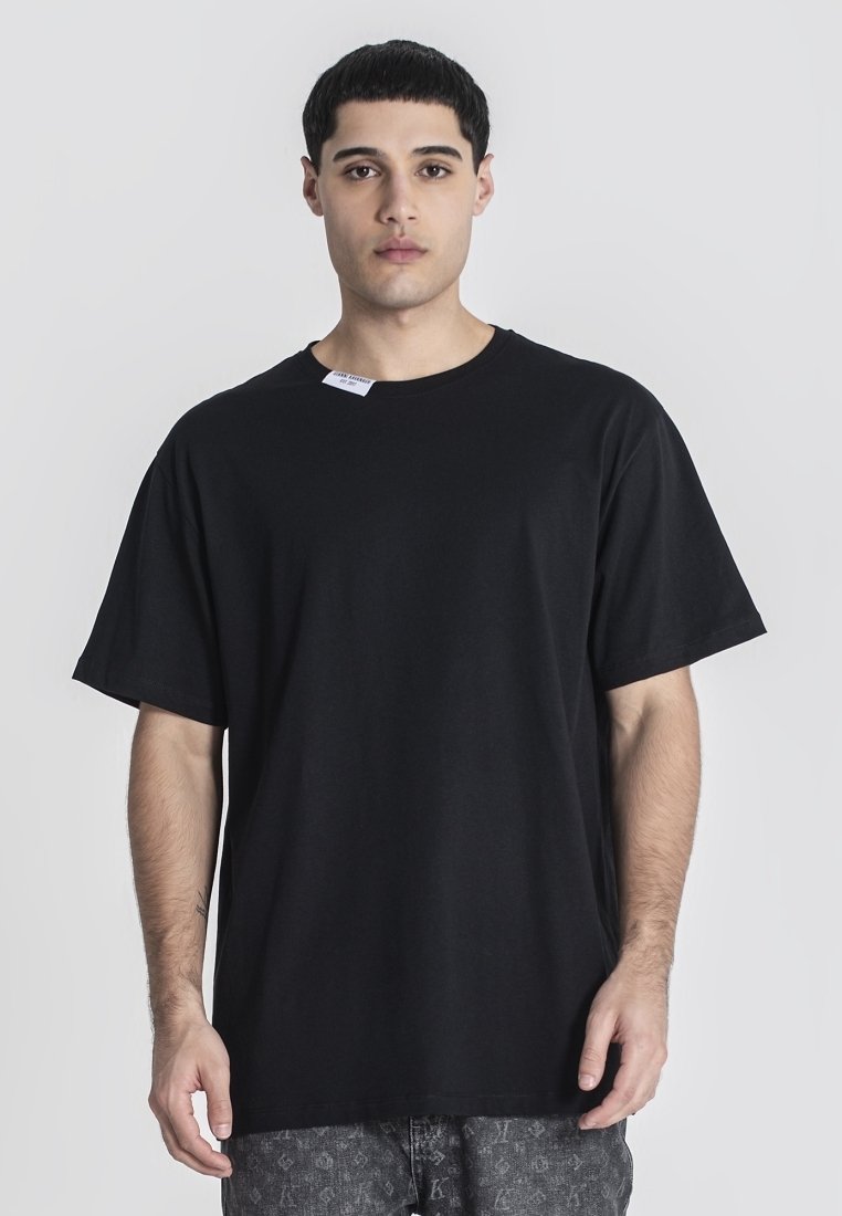 Camiseta de algodón negra con un corte holgado y mangas cortas, con un escote redondo y una pequeña etiqueta adjunta en el cuello.