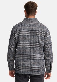 Plaid shirt made of woven fabric in dark blue, gray, and orange tones. Features a collar, long sleeves, and a straight cut.
