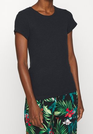 Black ribbed short-sleeve top with a round neckline and textured fabric. Worn with patterned floral pants featuring green leaves and red flowers.