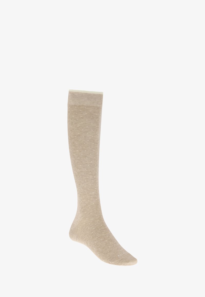 Chaussette beige montant jusqu'au genou avec de petits pois blancs, présentée à la verticale sur un fond blanc.