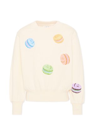 Bluza w kolorze kremowym z kolorowymi makaronikami w kształcie uśmiechniętych buziek z cekinami rozrzuconymi z przodu i na prawej rękawie.