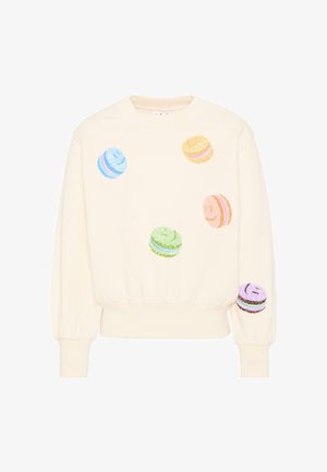 Bluza w kolorze kremowym z kolorowymi makaronikami w kształcie uśmiechniętych buziek z cekinami rozrzuconymi z przodu i na prawej rękawie.