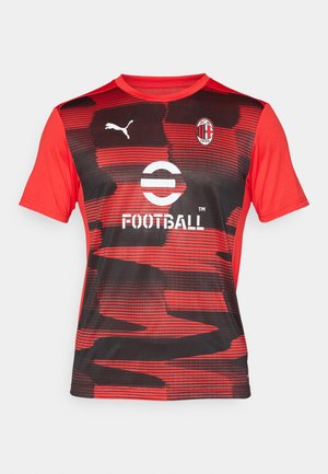 Raudona ir juoda trumpomis rankovėmis futbolo marškinėliai su bangų raštu, turintys apvalią kaklą, Puma logotipą ir klubo logotipą ant krūtinės.