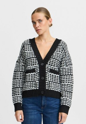 Cardigan a maglia con motivo bianco e nero, con scollatura a V profonda, polsini a coste e bottoni. Presenta ampie tasche e una finitura testurizzata.