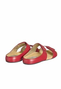 Chaussures en cuir rouge à dos ouvert, avec des côtés coupés en diagonale et une sangle à l'avant. Texture lisse avec une semelle intérieure beige et une semelle noire.
