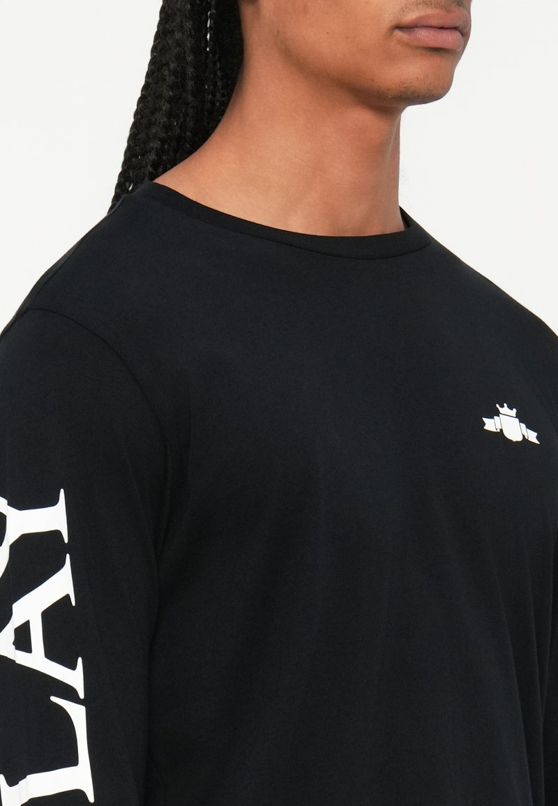 Schwarzes Langarm-T-Shirt mit kleinem Logo auf der Brust und großen weißen Text auf dem linken Ärmel, aus einem glatten Stoff gefertigt.