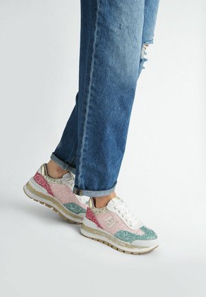 Sneakers multicolori scintillanti con accenti rosa, verdi e dorati. Presentano una suola bianca, lacci e un design chunky. Jeans in denim trattati.