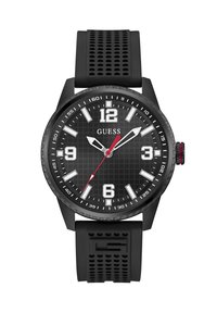 Black rubber strap watch with a textured black dial, bold white hour markers, red second hand, and stainless steel accents. Model: Guess.