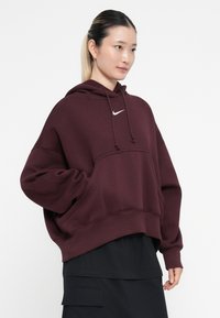 Sweatshirt oversized em bordeaux em material suave, com um bolso frontal, capuz com cordão e pequeno logótipo branco da Nike no peito.