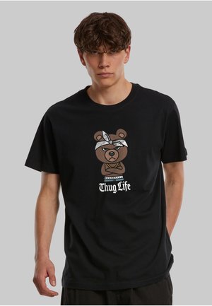 T-shirt en coton noir avec un motif d'ours brun portant un bandana et le texte "Thug Life" en blanc. Manches courtes et coupe décontractée.