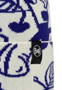 Knit beanie in cream with blue floral pattern. Features a black "Buff" logo tag. Made from soft, stretchy material.