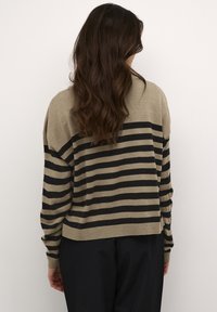 Khaki ja must triibuline sviiter, millel on mugav lõige, soonikkoes varrukad ja serv. Pehme tekstuur, langenud õlgade ja lühema seljaga.