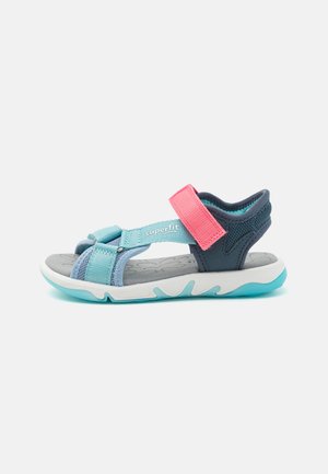 Marineblaue und hellblaue Sandale mit einem pinken Klettverschluss, gepolstertem grauem Fußbett und strukturiertem Gummisohle, die ein sicheres, offenes Design aufweist.
