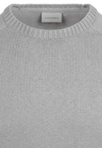 Hellgrauer Strickpullover mit einem gerippten Rundhalsausschnitt und Struktur, der ein einfaches Design aufweist und ein Etikett mit der Aufschrift "Suitable" auf der Rückseite hat.