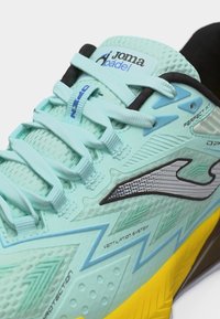 Ανοιχτό μπλε αθλητικό παπούτσι padel της Joma με κορδόνια, λεπτομέρειες συστήματος αερισμού και εμφανές κίτρινο πέλμα σε κοντινό πλάνο.