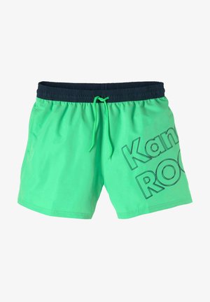 Green swim shorts with a navy elastic waistband and drawstring. Features a bold black print that reads "Kamal ROCK." Smooth texture.