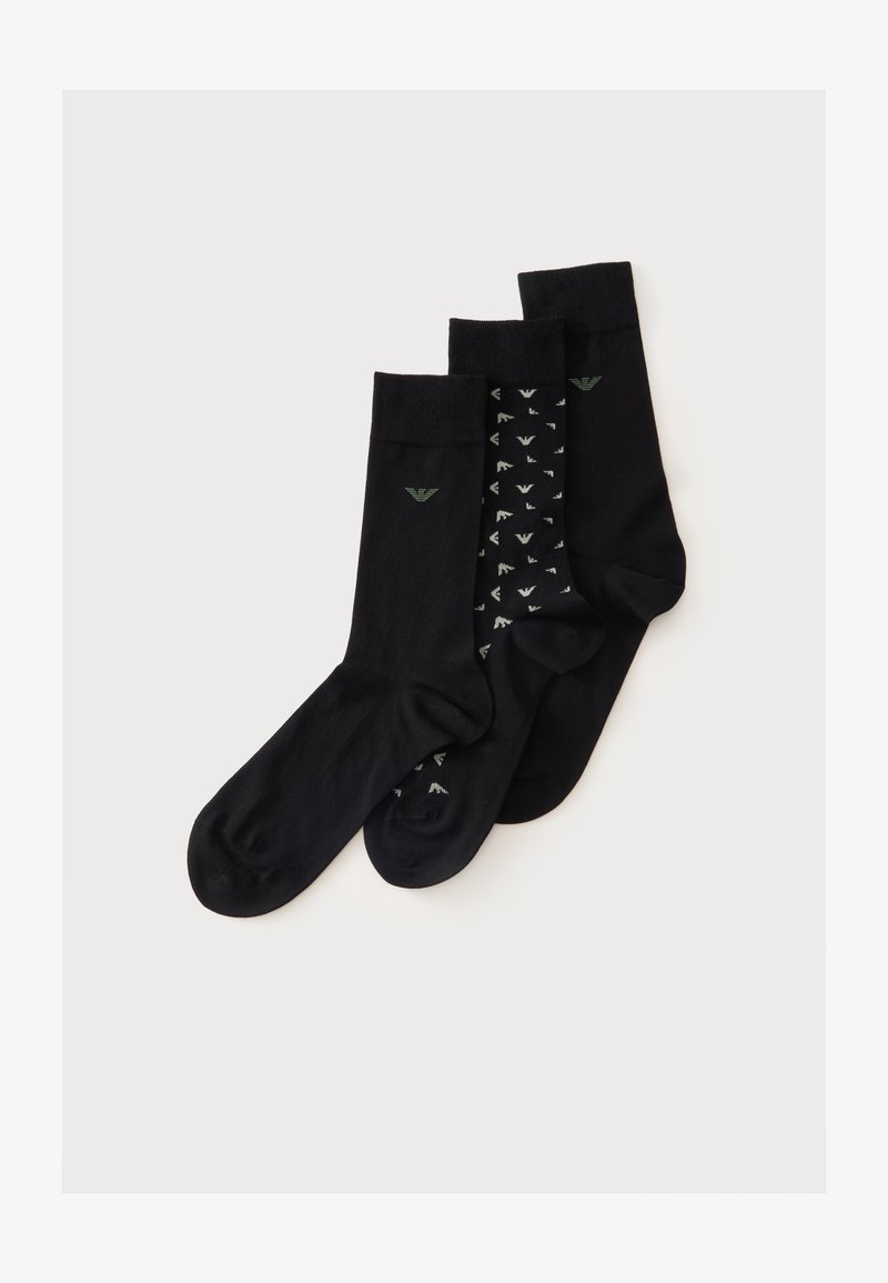 Trois chaussettes noires de type crew avec un petit logo vert, une chaussette présente un motif de petits logos blancs sur fond noir.