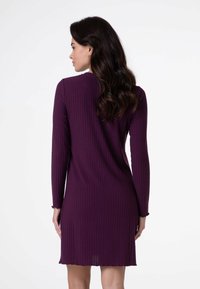 Abito a maniche lunghe, a coste, di un intenso colore viola. Presenta un orlo svasato e delicati polsini a scollatura, realizzato in morbido tessuto testurizzato.