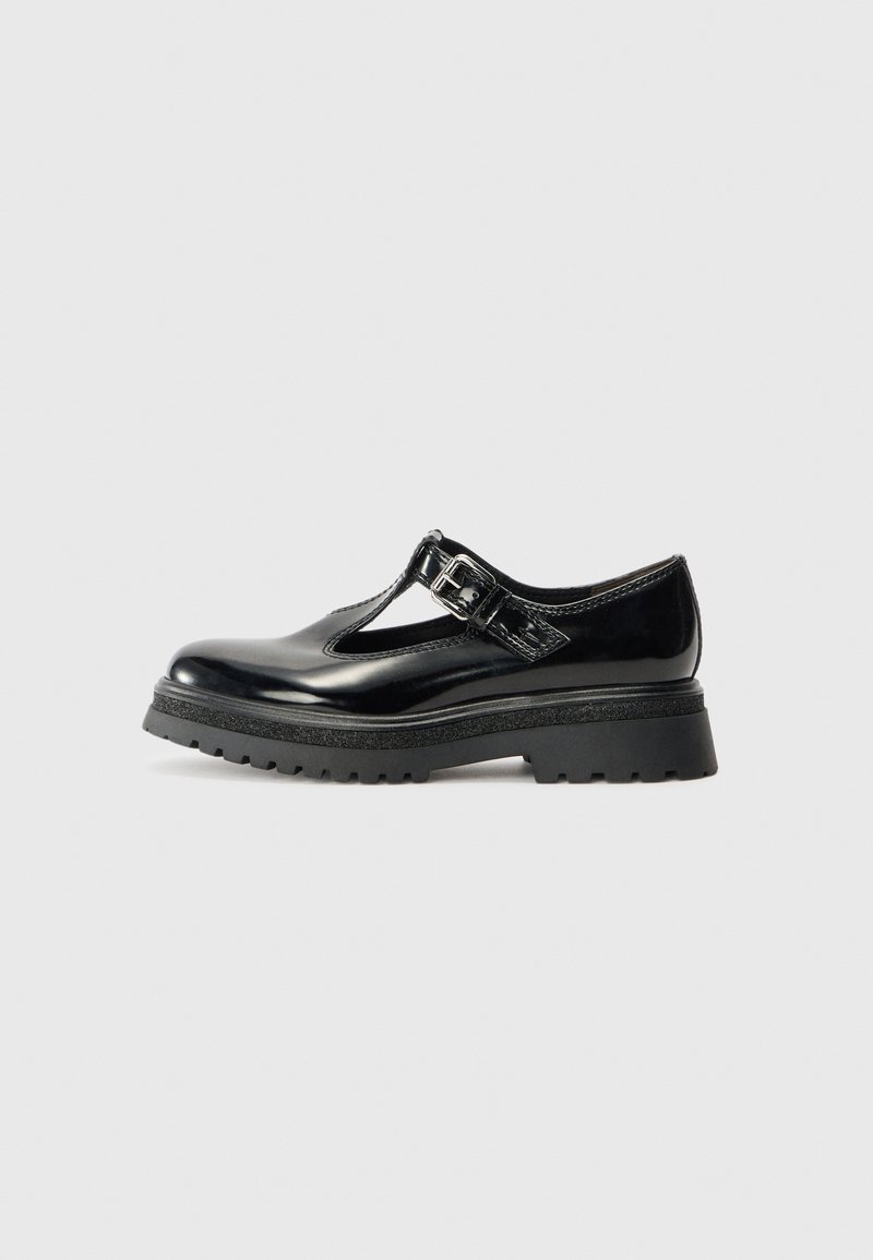 Chaussure Mary Jane en cuir noir brillant avec semelle crantée épaisse et bride à boucle argentée, vue de côté sur fond gris neutre.