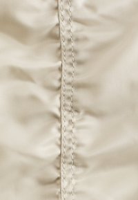 Beige fabric with a central seam featuring two parallel rows of stitches and slight wrinkling on either side.