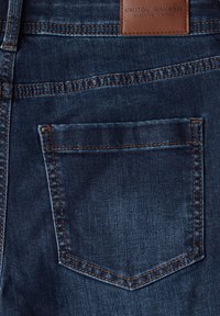 Jeans de mezclilla azul oscuro con un solo bolsillo trasero, costuras naranjas y una etiqueta de cuero marrón con la inscripción "Street One".