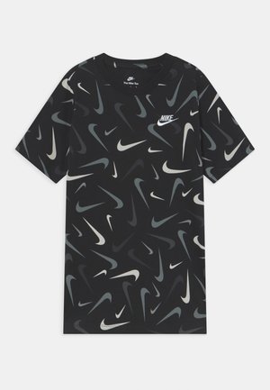 Sort Nike T-shirt med et mønster af forskellige nuancer af grå og hvide swoosh-logoer. Har rund hals og korte ærmer.