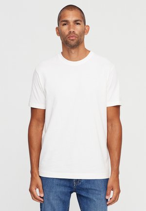 White cotton t-shirt with short sleeves and a round neckline, paired with blue denim jeans. Simple, solid color, and classic fit.