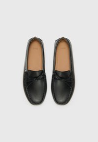 Schwarze Leder-Loafers mit glatter Textur, runder Zehenpartie, dekorativem Schleifenakzent und beigem Innenfutter. Gummisohle für besseren Halt.